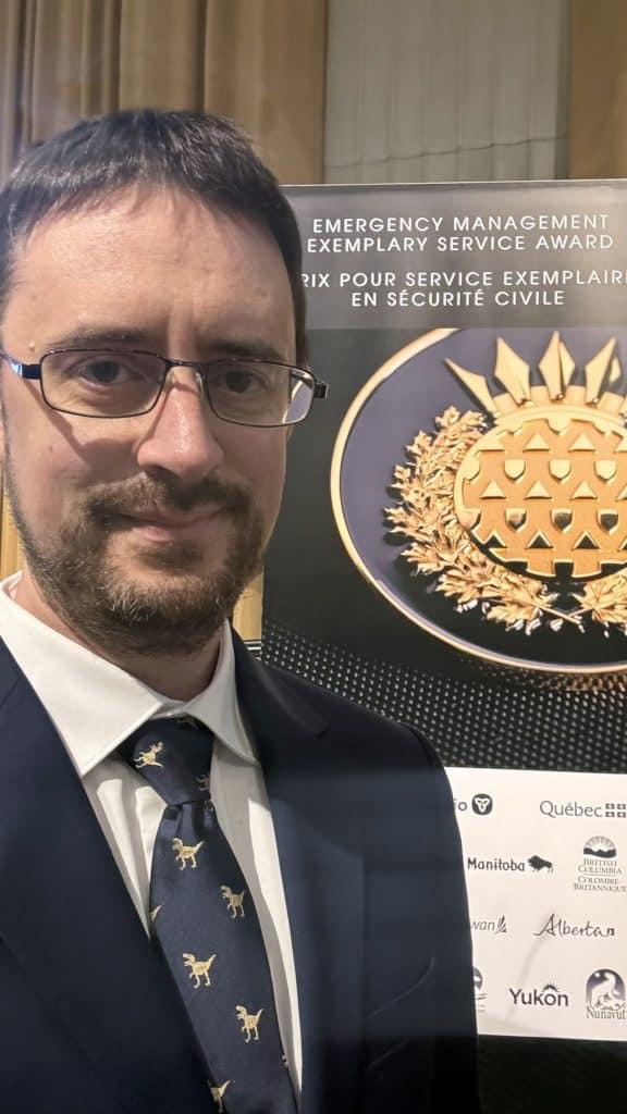 Man in a suit standing beside a logo of an award.