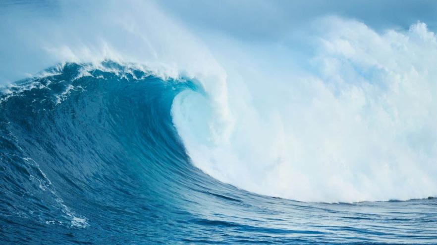 Large ocean wave crashing with blue and white frothy water.