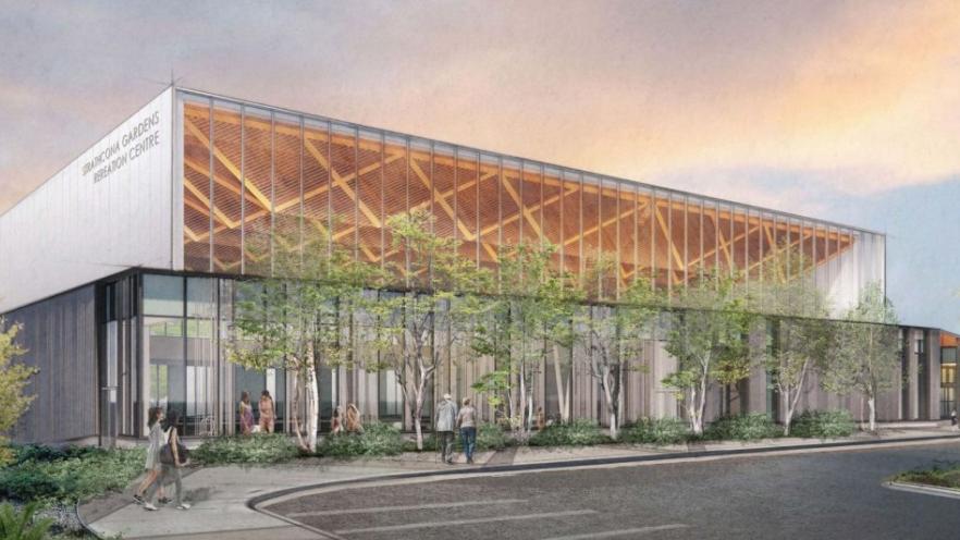 Modern building with glass walls, trees, and a sunset sky.