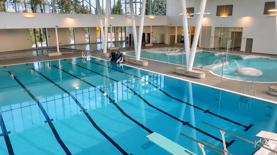 Bright indoor swimming pool with multiple lanes and large windows.