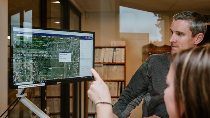 Two people discussing a map displayed on a computer screen in an office setting.