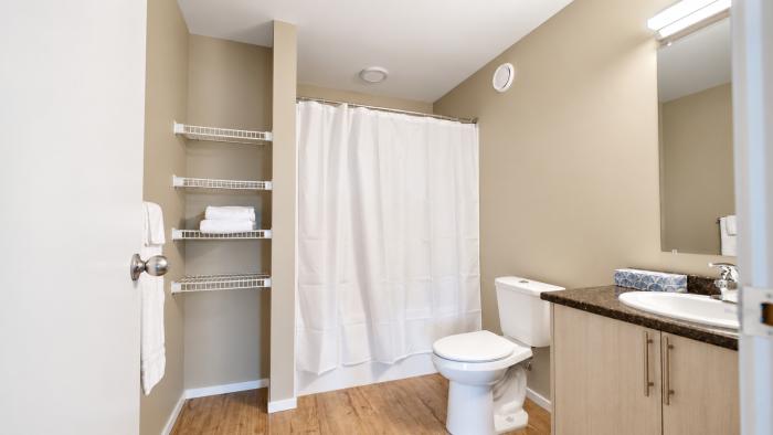 Bright bathroom featuring a toilet, sink, and shower with a white curtain.