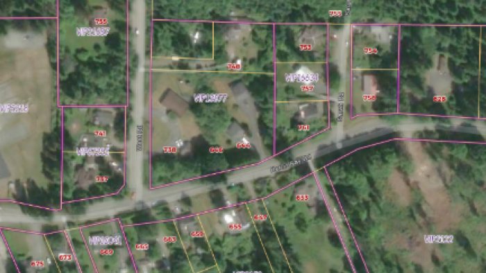 Aerial view of a residential area with houses, roads, and plotted land boundaries.