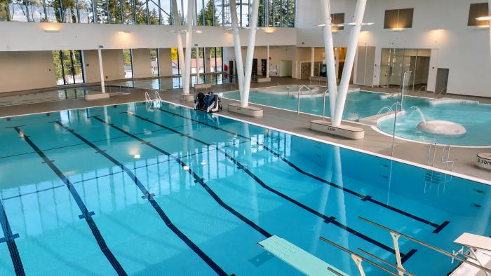 Bright indoor swimming pool with multiple lanes and large windows.
