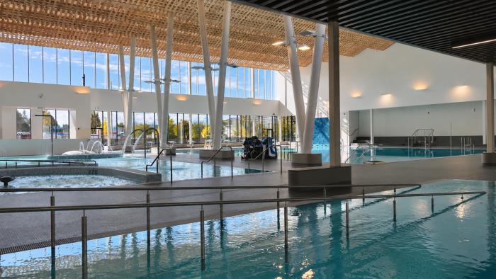 Indoor swimming pool with bright natural light, modern design, and multiple swim lanes.