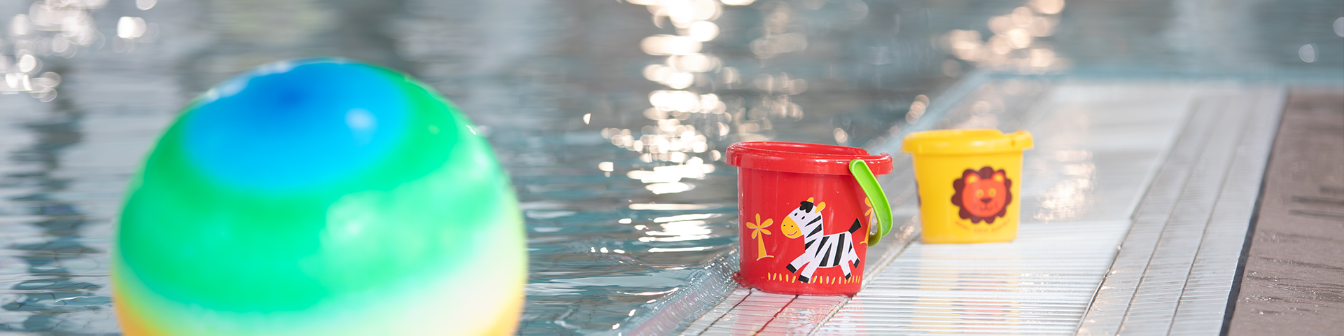 a ball and two buckets sitting on the edge of the pool deck