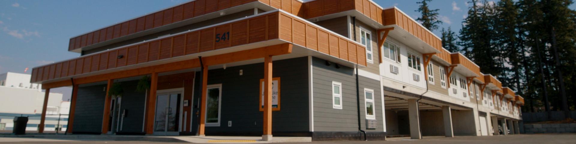 Modern building with wooden accents and large windows, set against a blue sky.