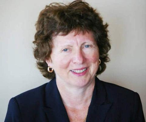 Claire Moglove, SRD Board Vice-Chair | Smiling woman with short curly hair wearing a dark blazer against a plain background.