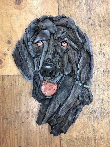 Driftwood dog sculpture on wooden surface.