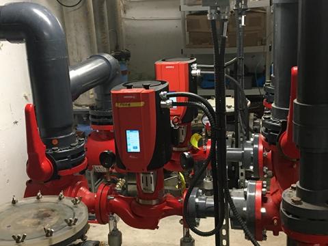 Red industrial pump system with pipes in a utility room.