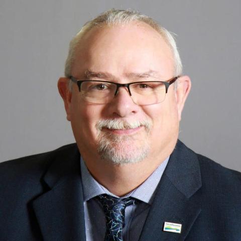Brad Unger, SRD Board Chair | Smiling man with glasses in a suit and tie.