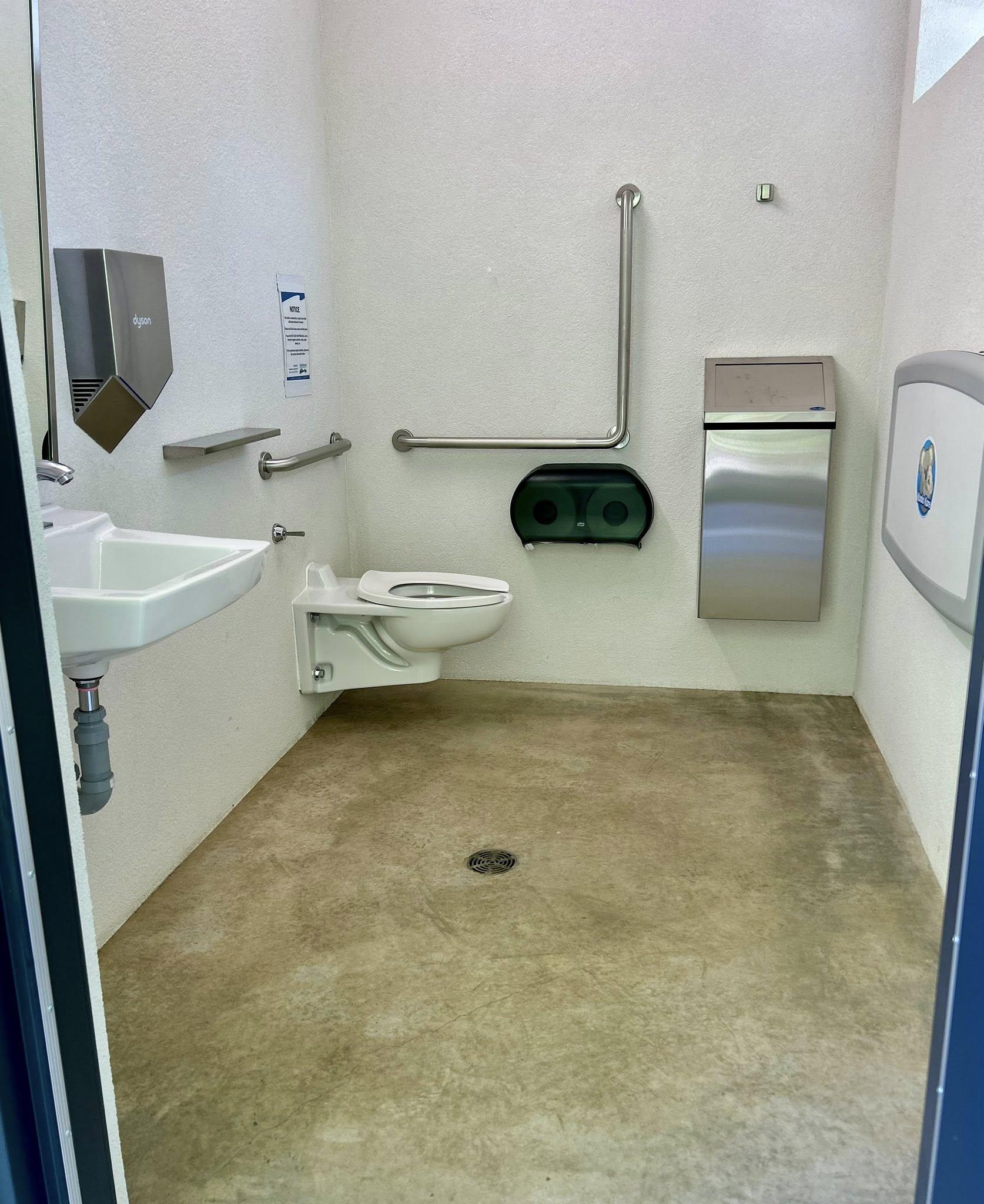Accessible restroom with toilet, sink, and grab bars.