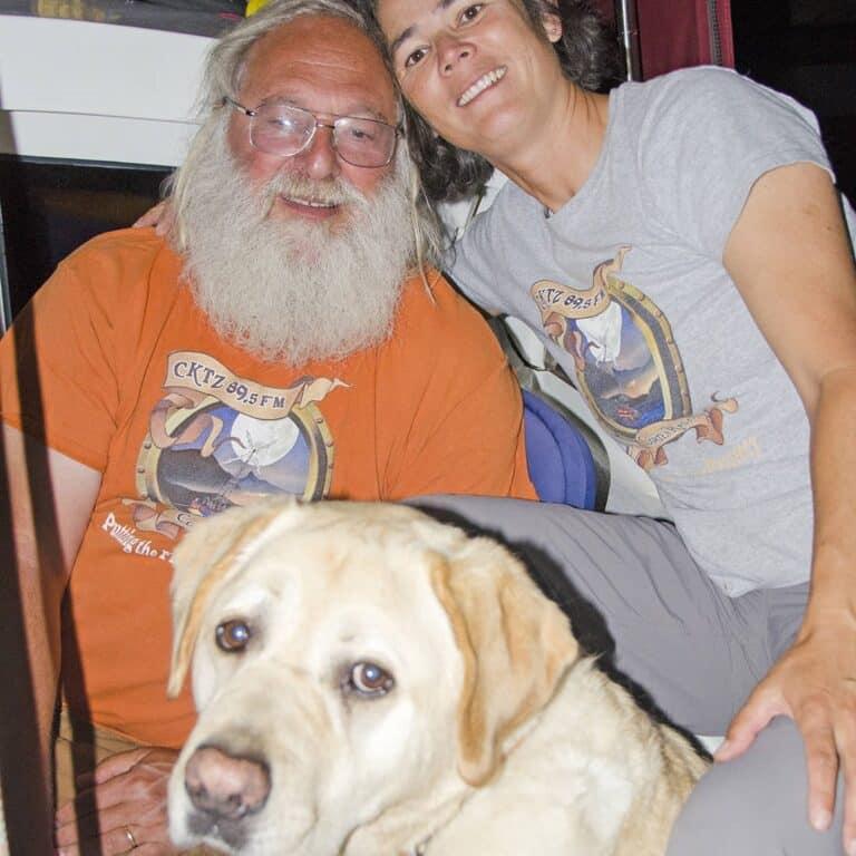 Smiling man and woman with Labrador dog indoors.
