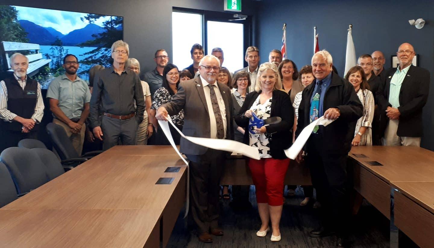 Group of people at a ribbon-cutting ceremony in a conference room.