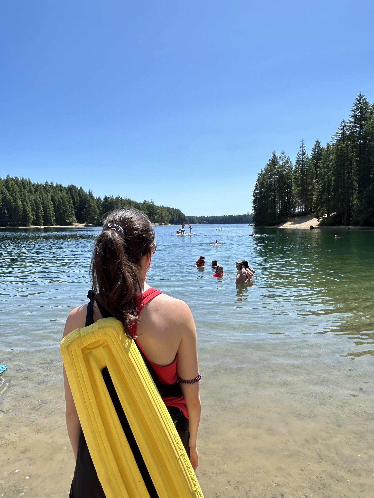 Lifeguard with swim float observing a lake on a sunny day.