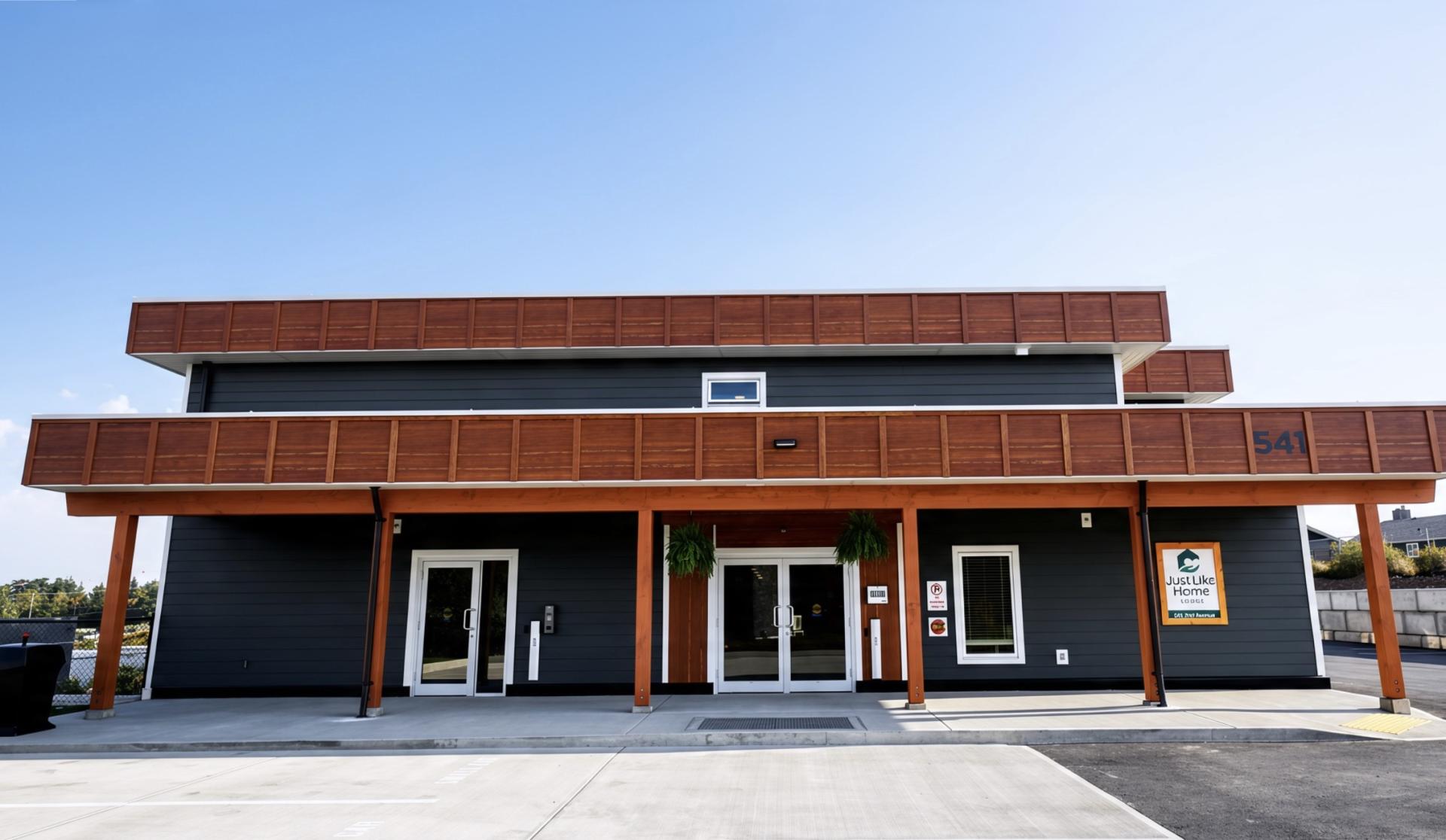 Modern two-story building with a wooden overhang and large glass doors.