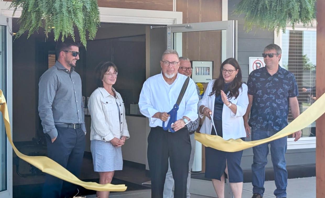 Group of people at a ribbon-cutting ceremony outside a building.